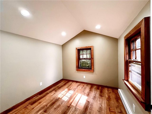 unfurnished room featuring hardwood / wood-style floors, a baseboard heating unit, and vaulted ceiling