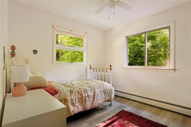 bedroom featuring baseboard heating, ceiling fan, and wood-type flooring