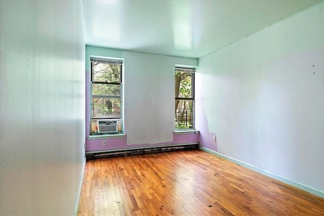 empty room with hardwood / wood-style flooring, cooling unit, and a baseboard radiator