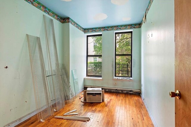 unfurnished bedroom with wood-type flooring and an AC wall unit