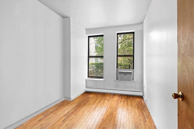 unfurnished room featuring cooling unit, light wood-type flooring, and a baseboard radiator