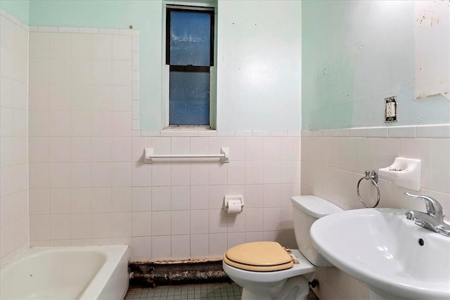 bathroom with a tub, sink, tile walls, and toilet