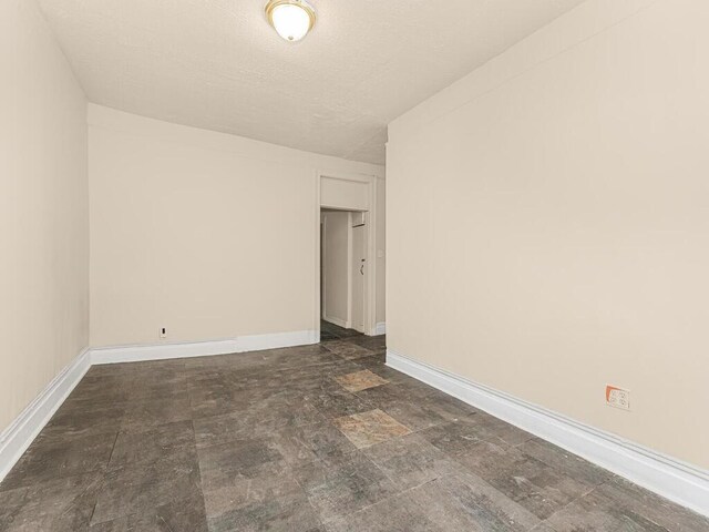 505 E 183rd St, Bronx, NY 10458 - spare room featuring baseboards, a textured ceiling, and stone finish floors