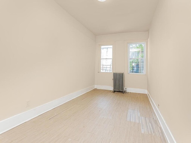 spare room featuring radiator and light wood-type flooring