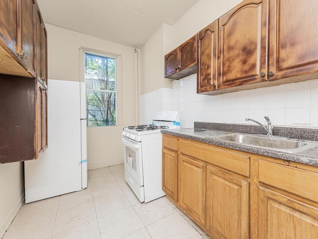 kitchen with light tile patterned flooring, white appliances, backsplash, and sink