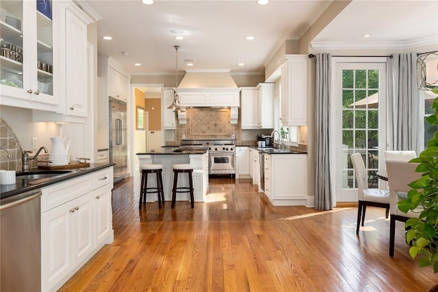 kitchen featuring high quality appliances, decorative light fixtures, sink, and white cabinets