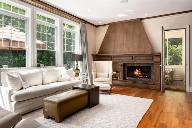 living area featuring ornamental molding, a high end fireplace, and light hardwood / wood-style flooring