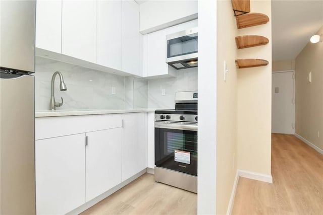 kitchen with white cabinetry, sink, decorative backsplash, appliances with stainless steel finishes, and light wood-type flooring