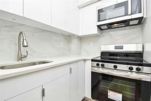 kitchen with appliances with stainless steel finishes, white cabinetry, and sink