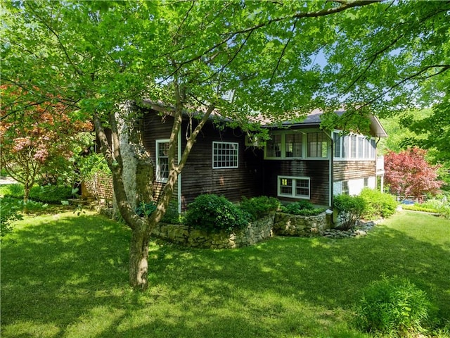 back of property with a sunroom and a lawn