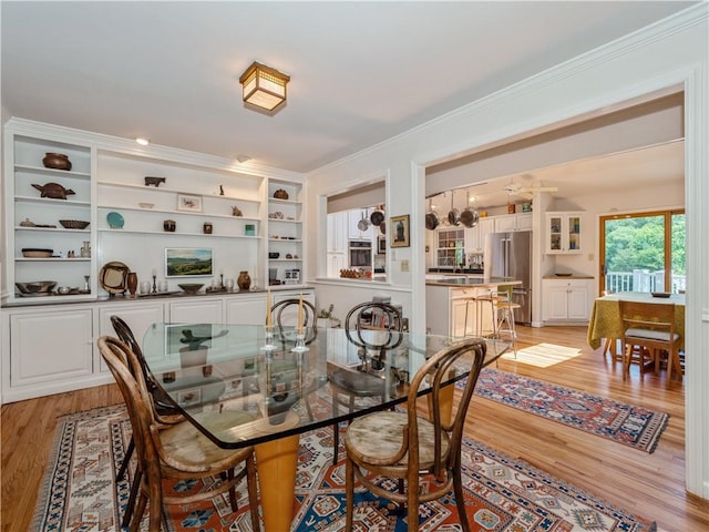 dining space with light wood-type flooring and crown molding