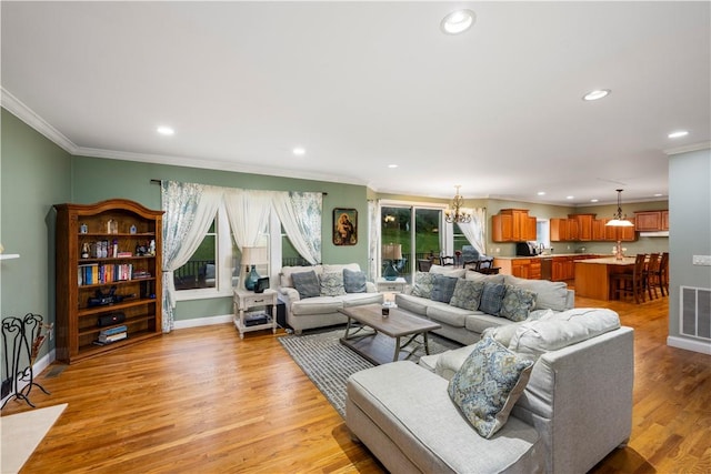 living room featuring an inviting chandelier, crown molding, and light hardwood / wood-style flooring