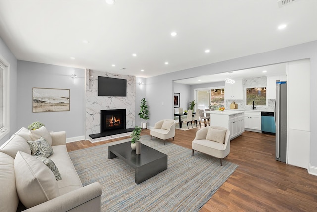 living room with wood-type flooring, sink, and a high end fireplace