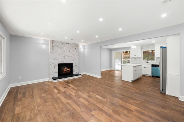 unfurnished living room featuring a high end fireplace, sink, and hardwood / wood-style floors