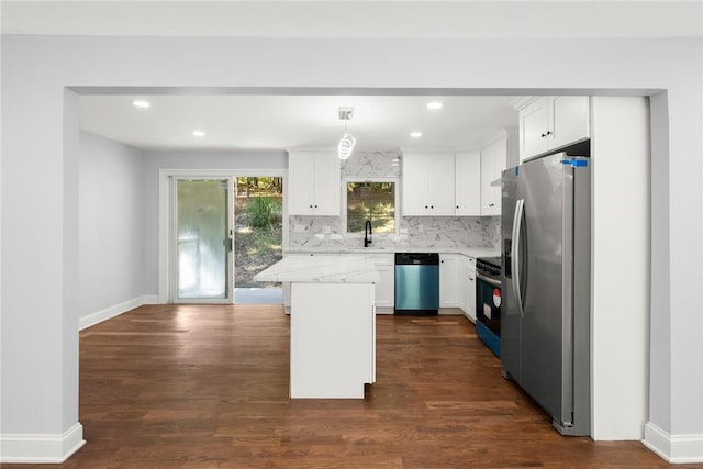 kitchen with pendant lighting, stainless steel appliances, a kitchen island, and white cabinets