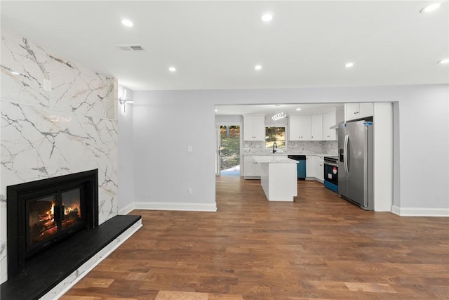 unfurnished living room featuring a fireplace, dark hardwood / wood-style flooring, and sink