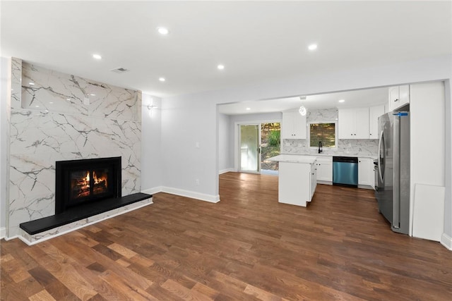 kitchen featuring a fireplace, white cabinetry, backsplash, dark hardwood / wood-style flooring, and stainless steel appliances