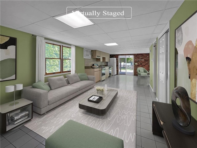 tiled living room with a paneled ceiling, a wealth of natural light, and sink