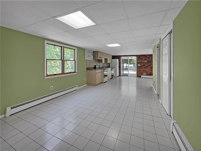 unfurnished living room featuring baseboard heating, a drop ceiling, and light tile patterned floors