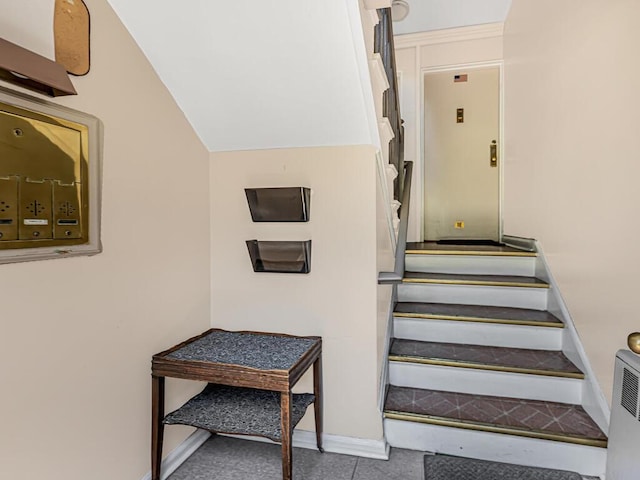 stairs featuring tile patterned flooring and vaulted ceiling