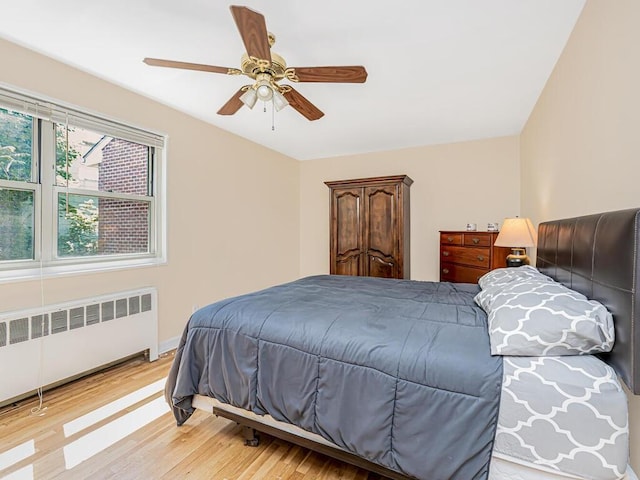 bedroom with radiator heating unit, ceiling fan, and hardwood / wood-style floors