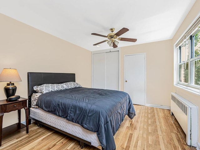 bedroom with ceiling fan, light wood-type flooring, and radiator heating unit