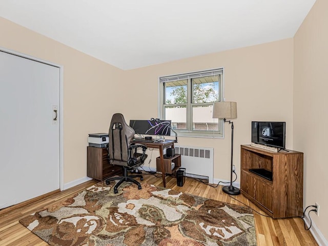 office space with light hardwood / wood-style floors and radiator heating unit