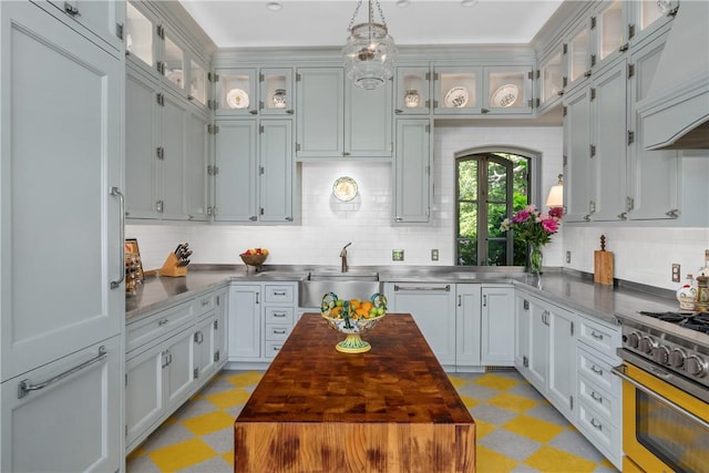 kitchen with high end stainless steel range oven, pendant lighting, dishwasher, white cabinetry, and butcher block counters