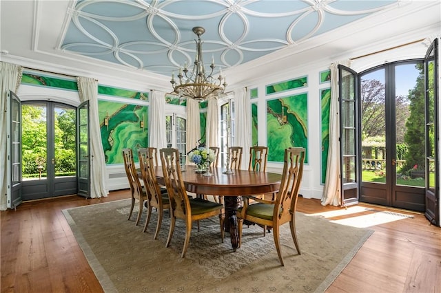 dining room with french doors, hardwood / wood-style flooring, an inviting chandelier, and ornamental molding