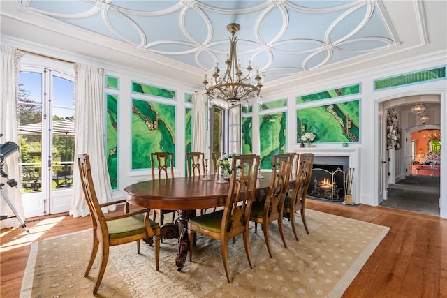 dining area with hardwood / wood-style flooring, ornamental molding, and a notable chandelier