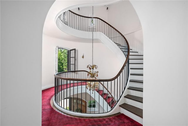 stairs with carpet flooring and a notable chandelier