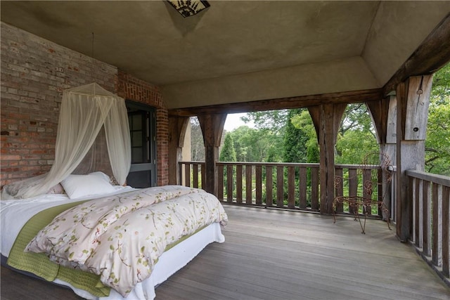 bedroom featuring light hardwood / wood-style floors and brick wall