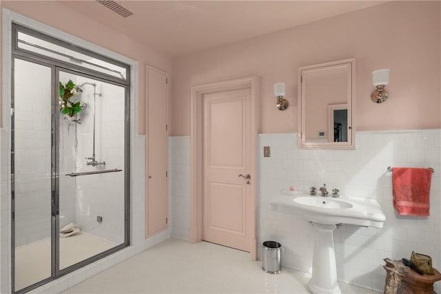 bathroom with a shower with door and tile walls