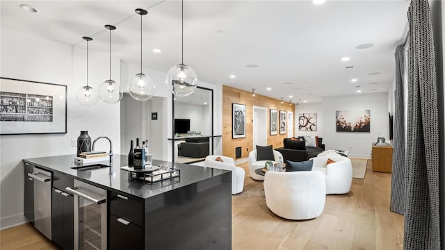 kitchen featuring wine cooler, sink, pendant lighting, and light wood-type flooring