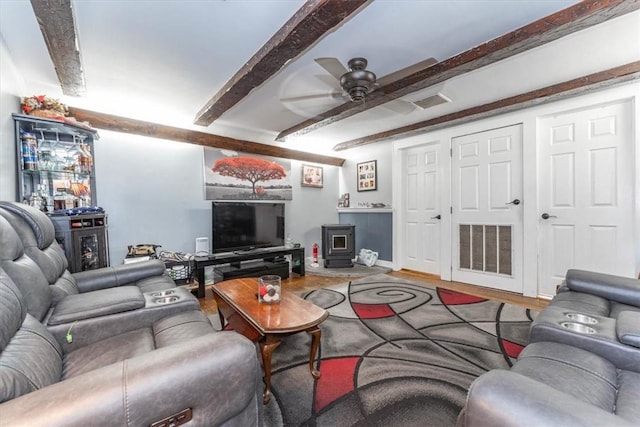 living room featuring beamed ceiling, ceiling fan, wood-type flooring, and a wood stove