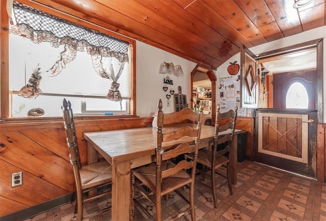 dining area with wooden walls, lofted ceiling, and wood ceiling