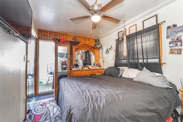 carpeted bedroom with ceiling fan and wooden walls