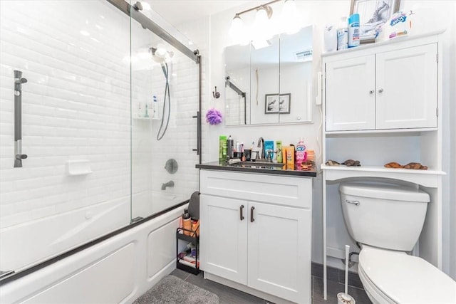 full bathroom with combined bath / shower with glass door, vanity, and toilet