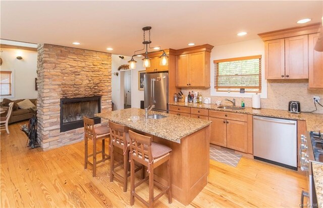 kitchen featuring stainless steel appliances, a breakfast bar area, a center island with sink, and light hardwood / wood-style floors