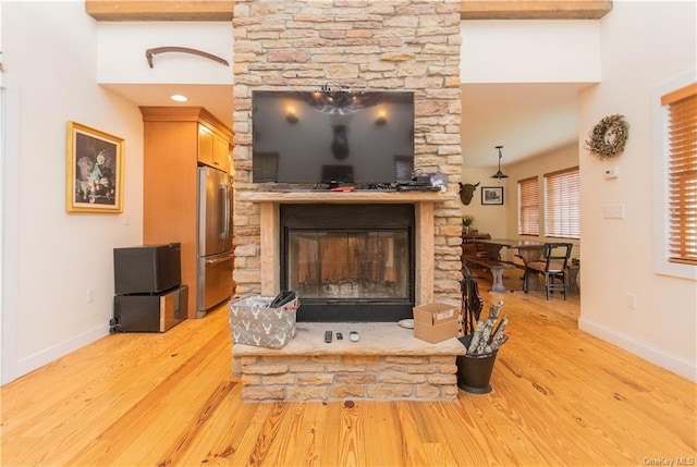 interior details featuring a stone fireplace, wood-type flooring, and stainless steel refrigerator