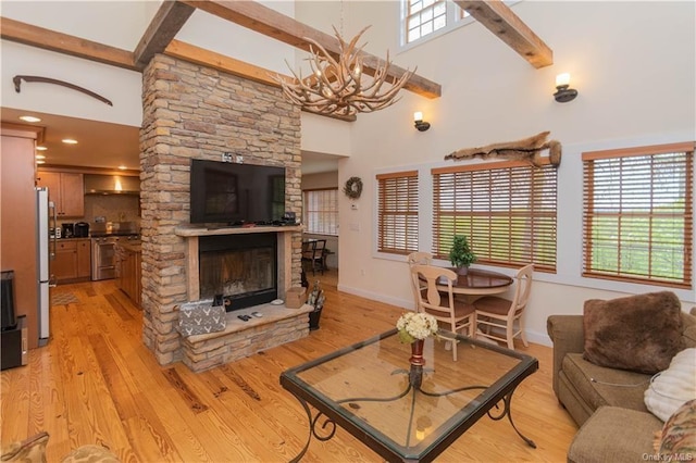 living room with a stone fireplace, plenty of natural light, light hardwood / wood-style floors, and a high ceiling