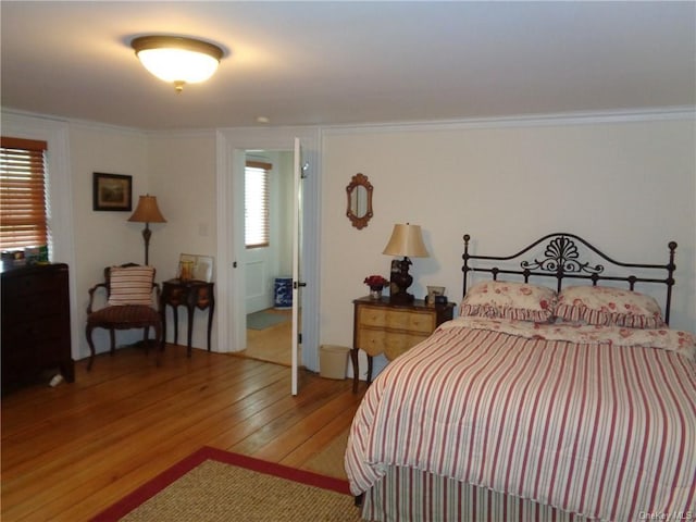 bedroom with wood-type flooring, crown molding, and multiple windows