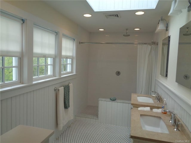 bathroom featuring vanity, a skylight, tile patterned flooring, a tile shower, and radiator heating unit