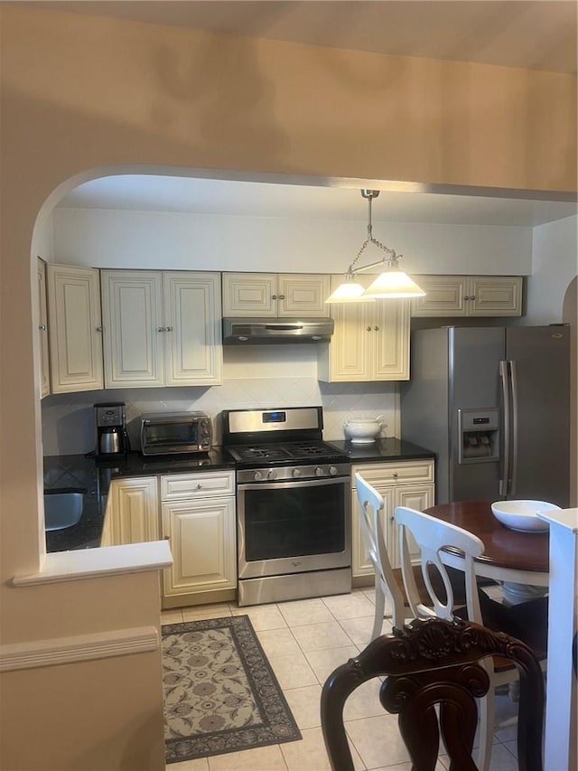 kitchen featuring pendant lighting, backsplash, cream cabinets, light tile patterned floors, and stainless steel appliances