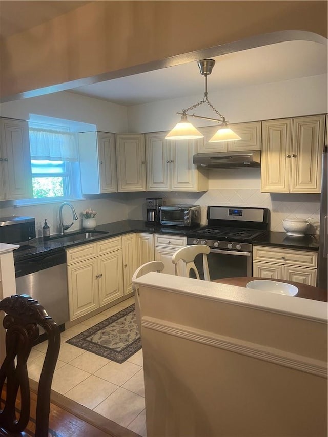 1357 Waring Ave, Bronx, NY 10469 - kitchen with stainless steel appliances, a sink, under cabinet range hood, dark countertops, and backsplash
