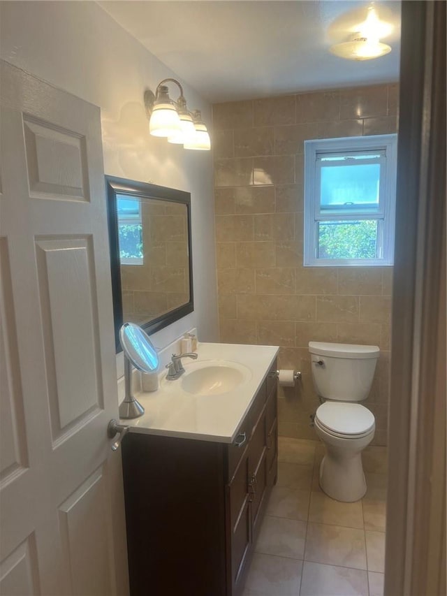 bathroom with toilet, vanity, tile patterned floors, and tile walls