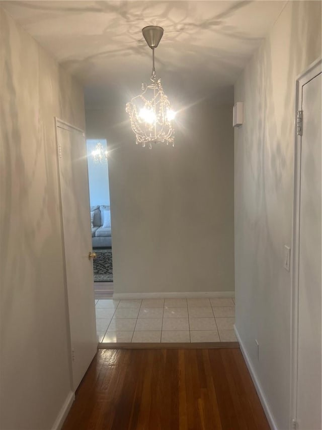 corridor with a notable chandelier and wood-type flooring