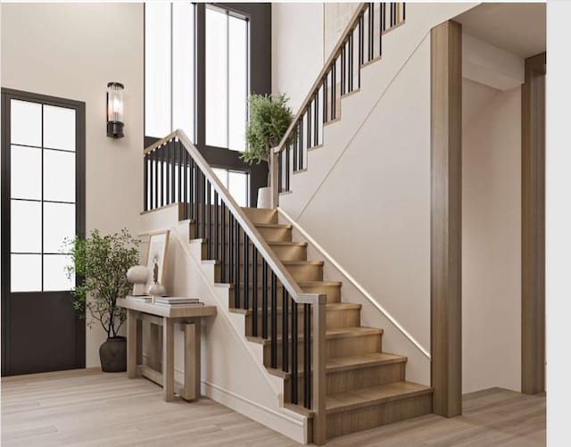 stairs featuring wood-type flooring and a towering ceiling