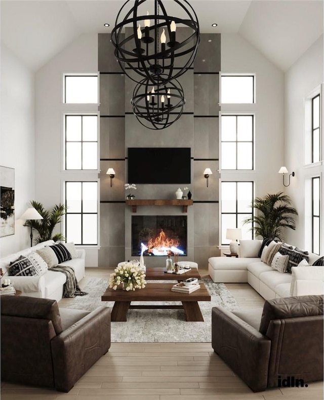 living room featuring a fireplace, high vaulted ceiling, wood-type flooring, and an inviting chandelier