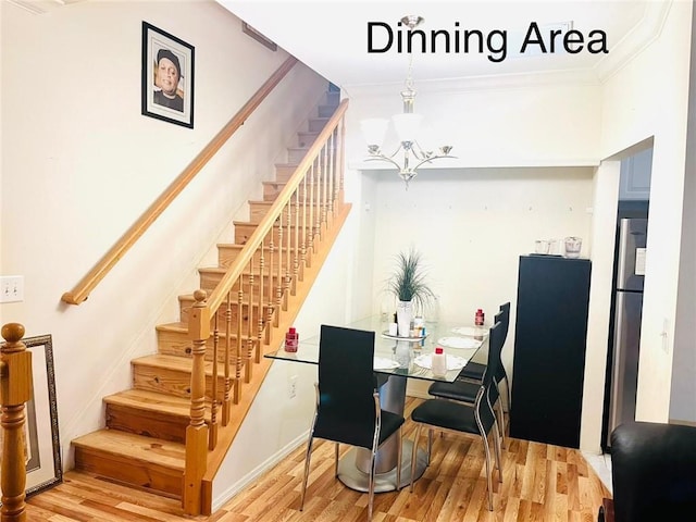 dining area with wood-type flooring, an inviting chandelier, and crown molding